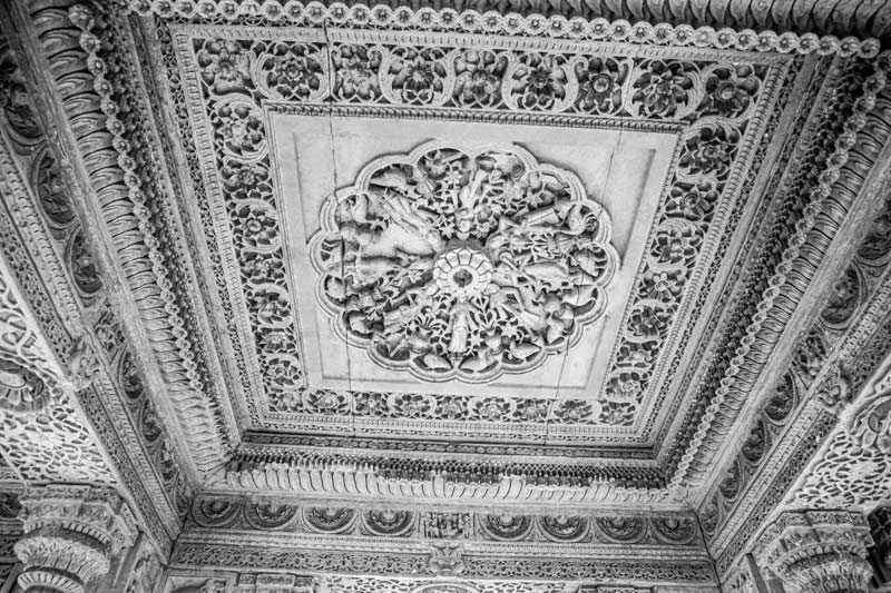 A ceiling panel displaying carvings of multiple celestial beings, birds and floral designs inside a pavilion on Rajsamand embankment
